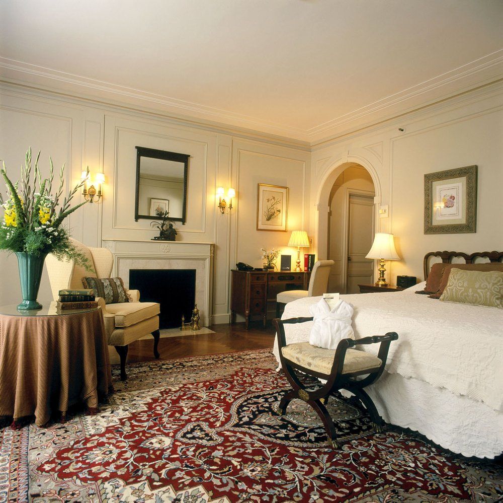 Mansion guest room with fireplace, floral arrangement and oriental rug